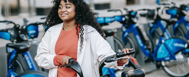 A woman happy to rent an electric blue bike