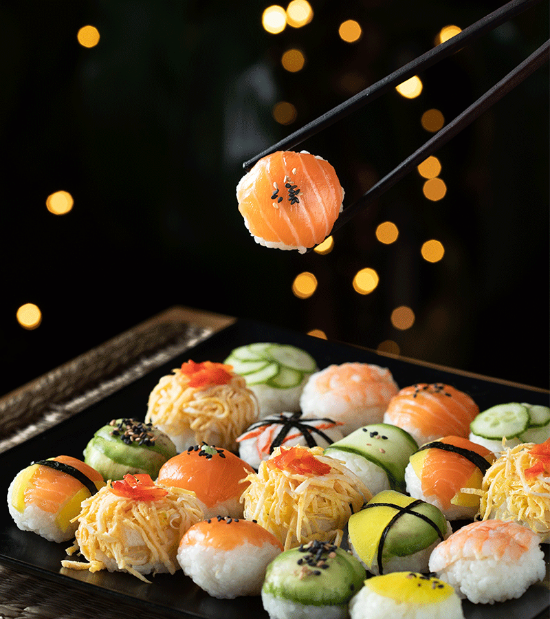 A young woman covering her eyes with sushi in a playful way